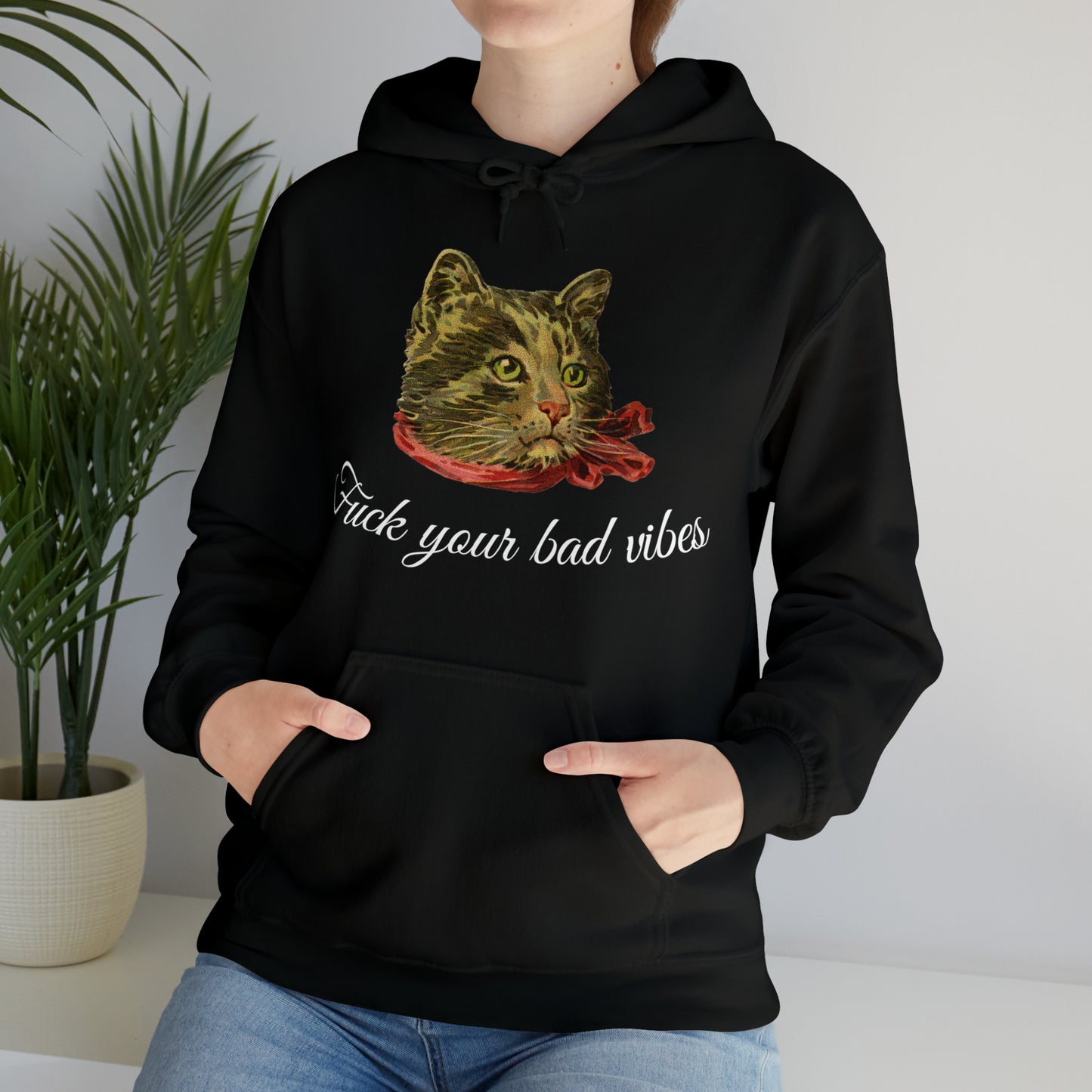 woman wearing black hoodie featuring the phrase "Fuck Your Bad Vibes" in elegant cursive beneath a charming vintage graphic of a stylish cat sporting a scarf