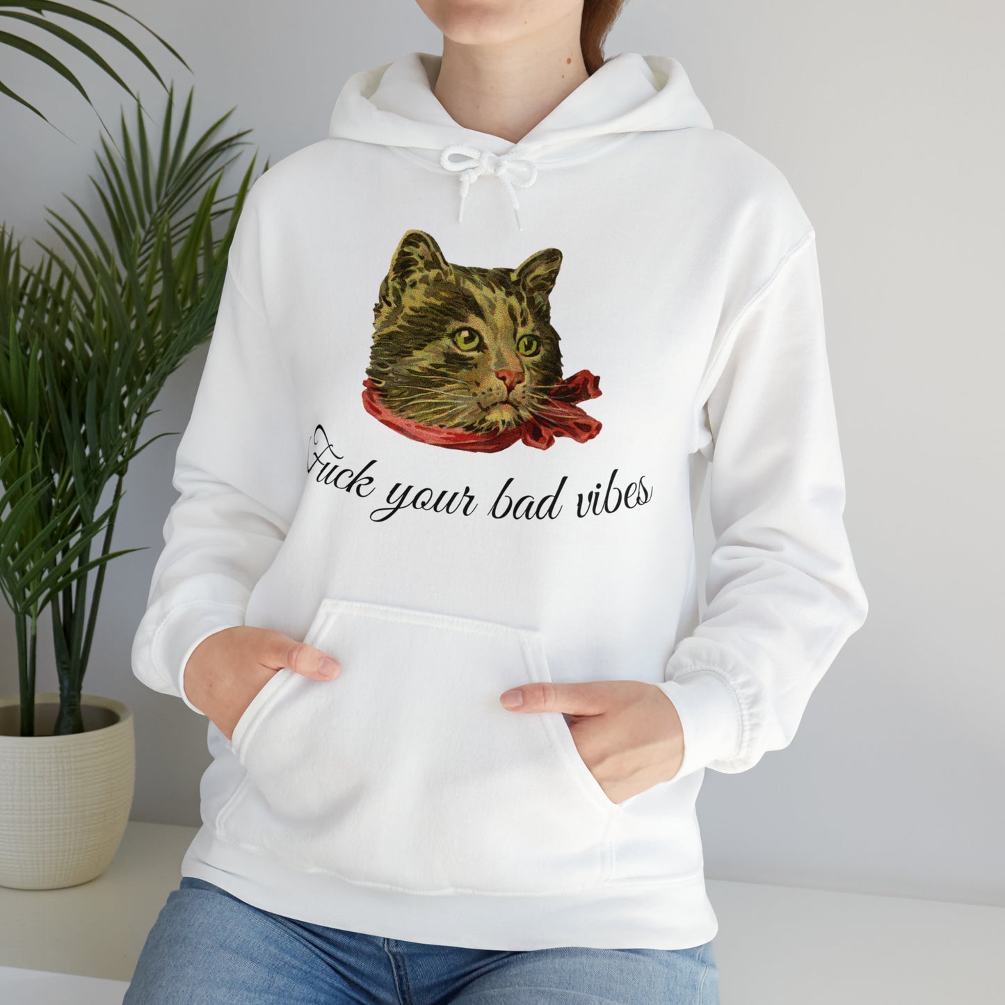 woman wearing white hoodie featuring the phrase "Fuck Your Bad Vibes" in elegant cursive beneath a charming vintage graphic of a stylish cat sporting a scarf