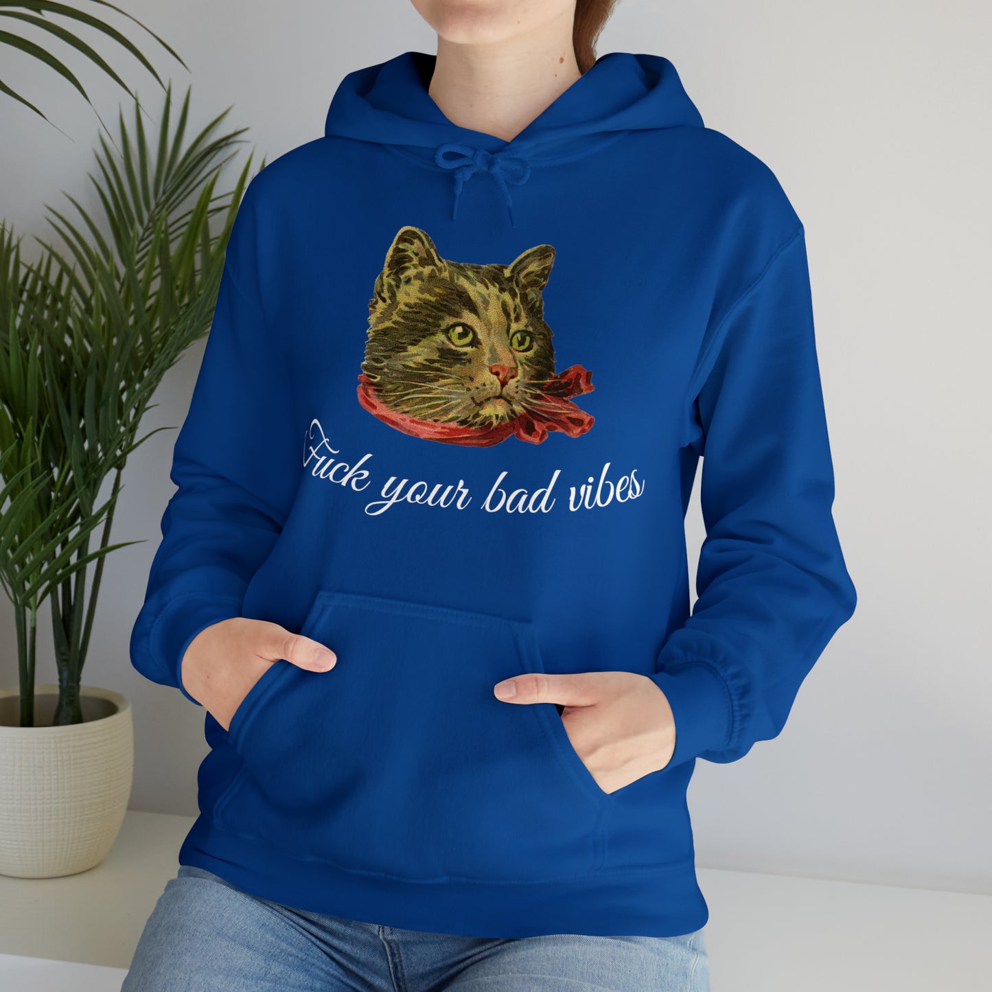 woman wearing blue hoodie featuring the phrase "Fuck Your Bad Vibes" in elegant cursive beneath a charming vintage graphic of a stylish cat sporting a scarf