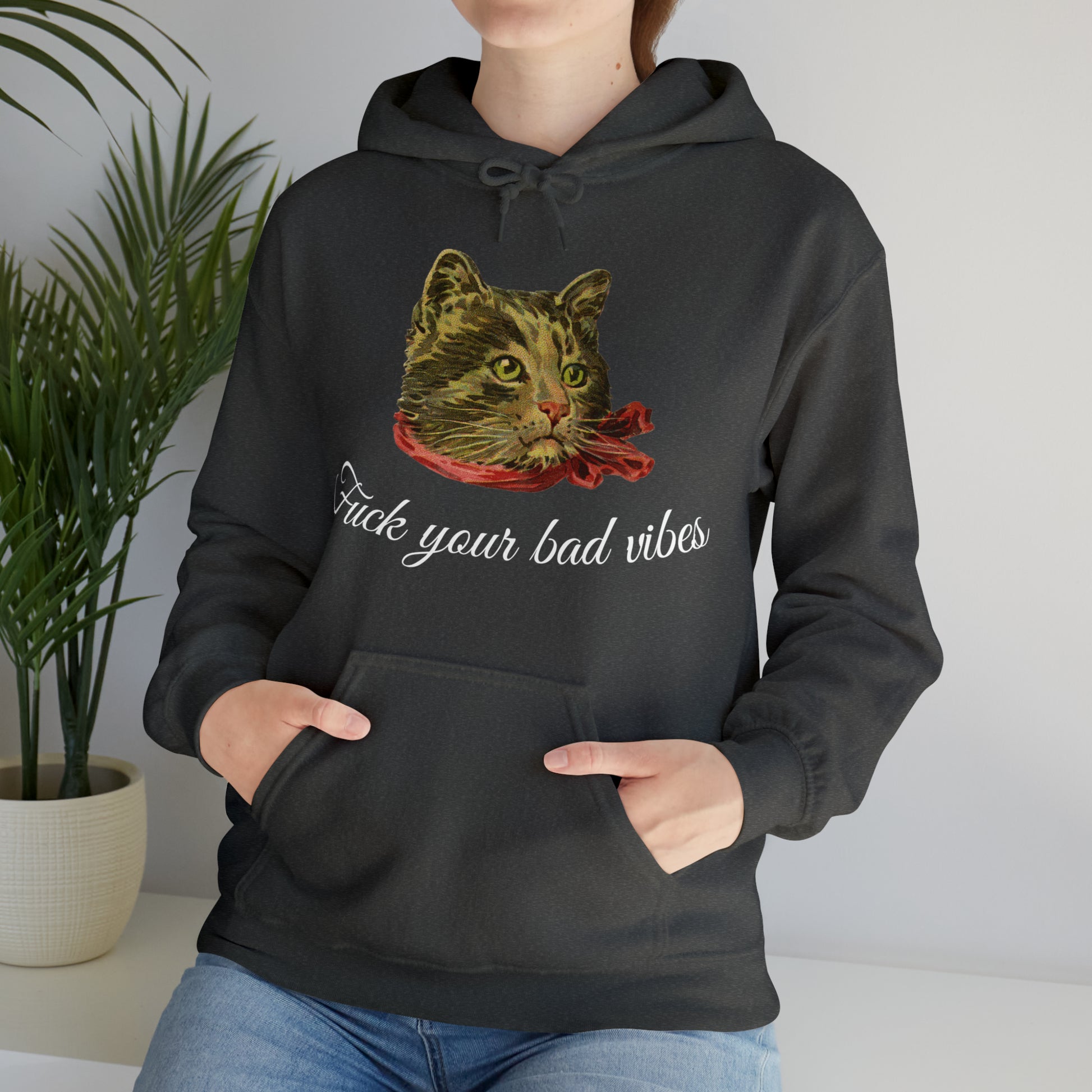 woman wearing dark gray hoodie featuring the phrase "Fuck Your Bad Vibes" in elegant cursive beneath a charming vintage graphic of a stylish cat sporting a scarf