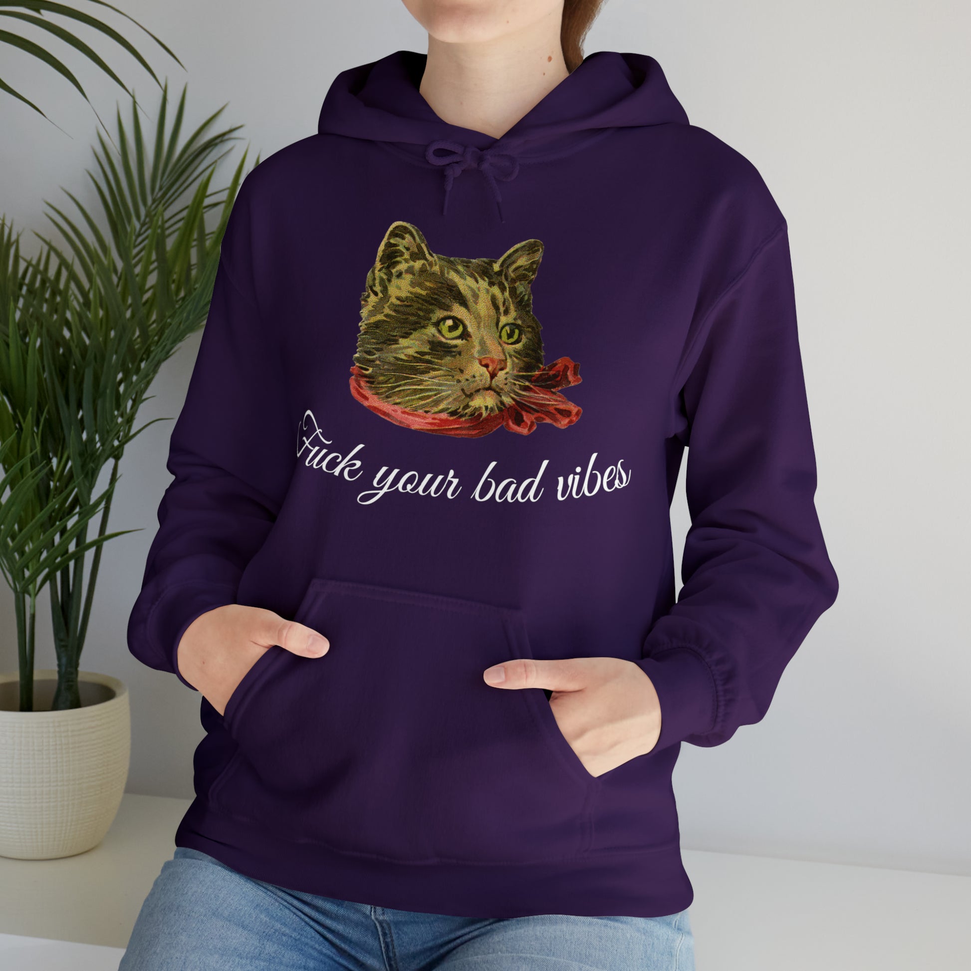 woman wearing purple hoodie featuring the phrase "Fuck Your Bad Vibes" in elegant cursive beneath a charming vintage graphic of a stylish cat sporting a scarf