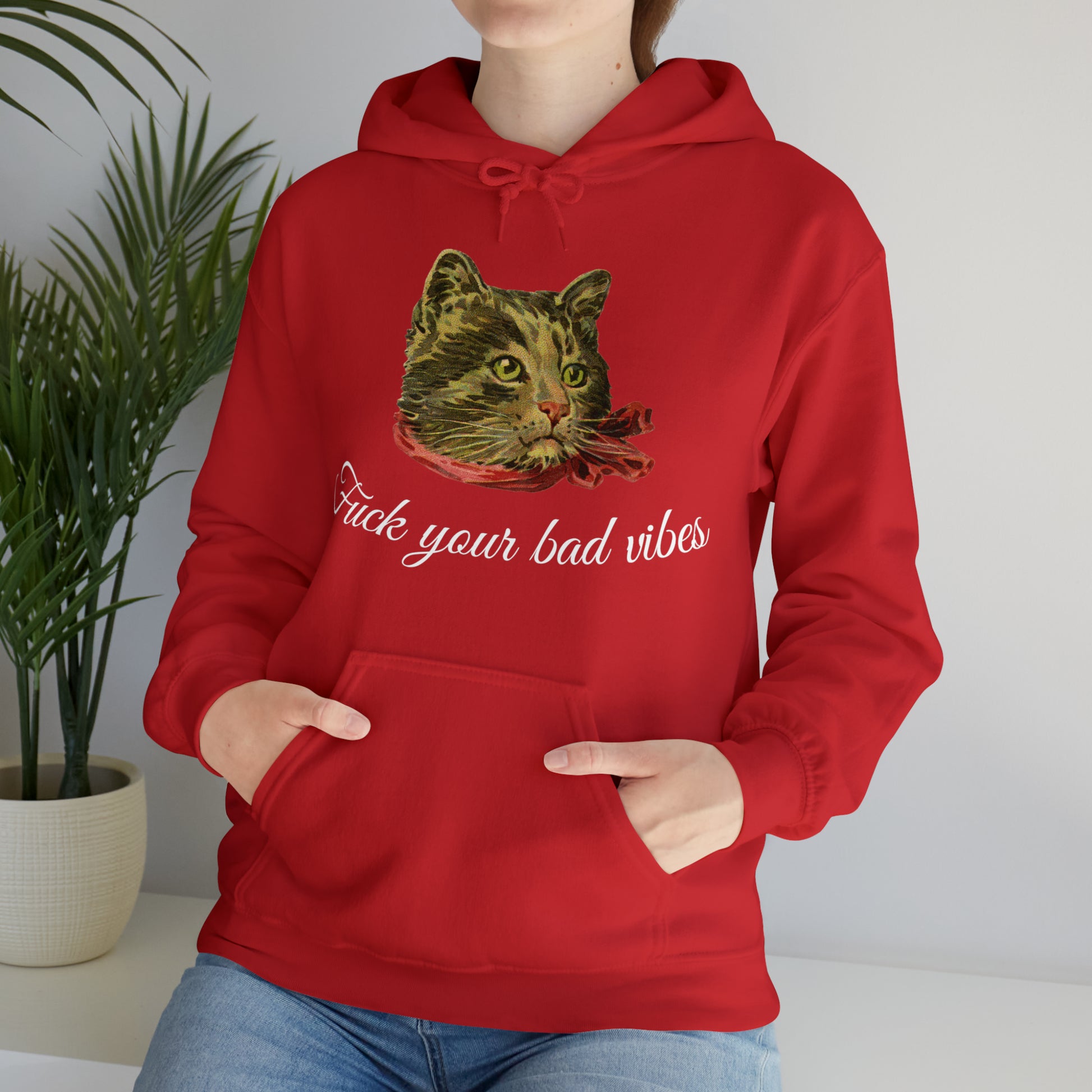 woman wearing red hoodie featuring the phrase "Fuck Your Bad Vibes" in elegant cursive beneath a charming vintage graphic of a stylish cat sporting a scarf